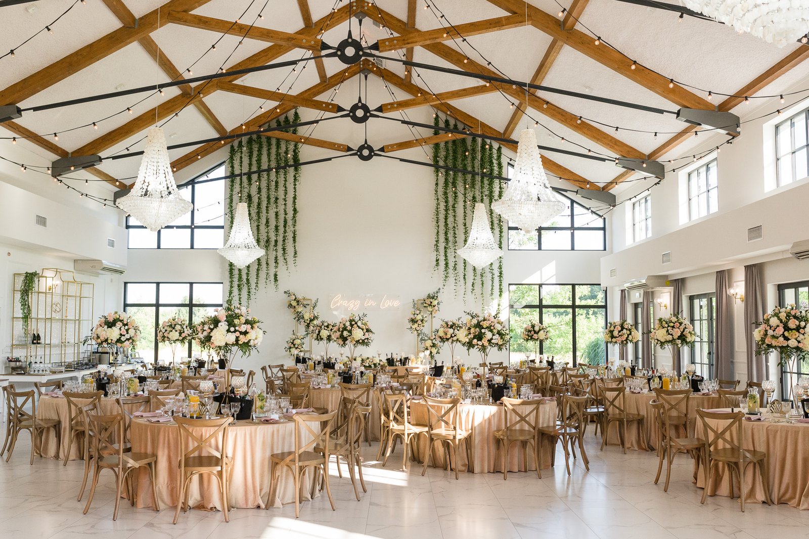 Sala weselna Pastelove Pola niedaleko Warszawy w dniu przyjęcia weselnego, udekorowana jest kompozycjami kwiatowymi, widać okrągłe stoły z beżowymi obrusami